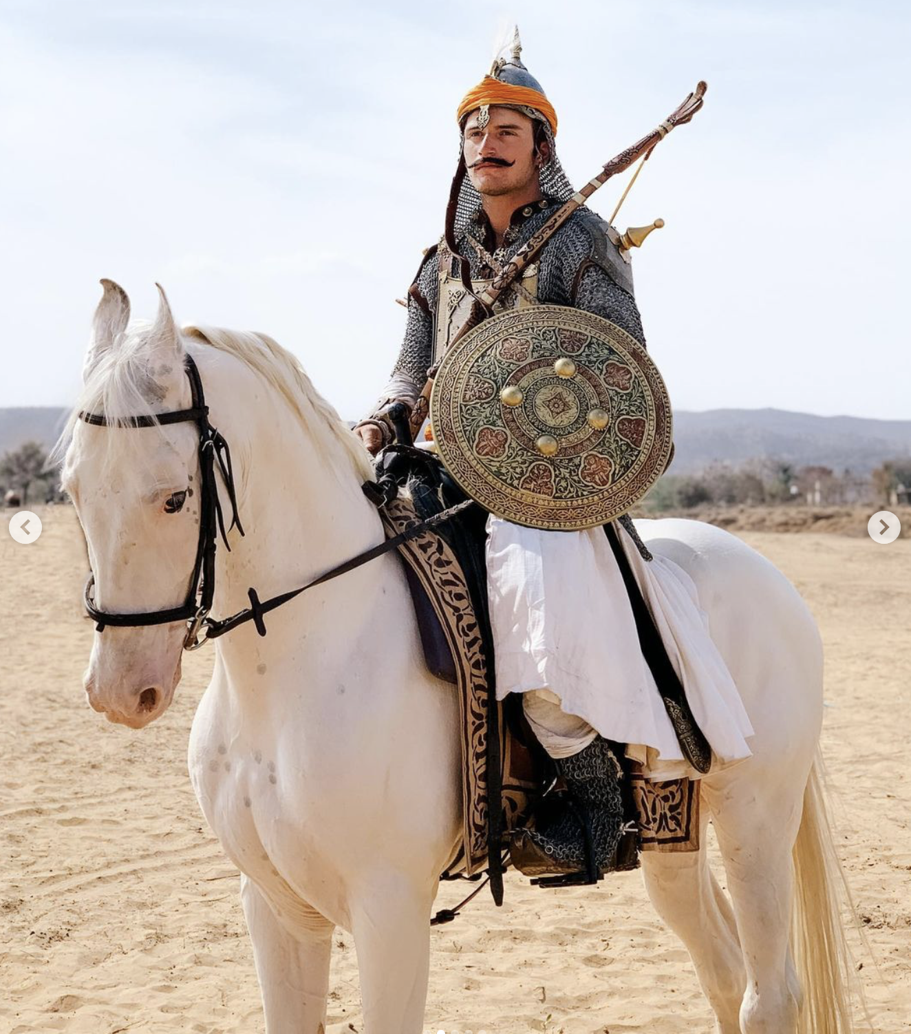 Indian warrior stunt double dressed in armour on a white horse for a movie scene in a desert setting