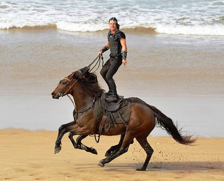 Stunt performer practicing Roman riding on two horses during training for a film stunt