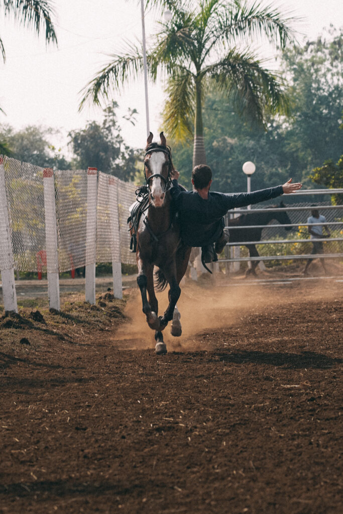 Skilled trick rider practicing a vaulting move on a horse during training for film stunts